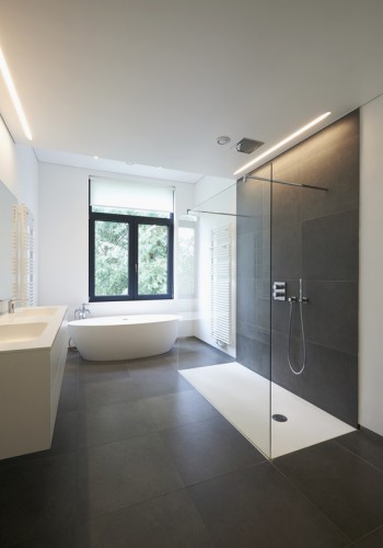 Bathtub in corian, Faucet and shower in tiled bathroom with windows towards garden